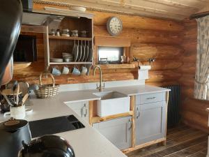 Una cocina con un fregadero y un reloj en la pared. en Rowan - Tedstone Log Cabins, en Bromyard