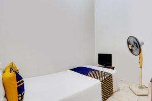 a bedroom with a bed with a fan and a desk at OYO Life 91893 Kost Jeje Syariah in Tambak-kidul