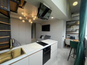 a kitchen with white cabinets and a tv on the ceiling at Mondden Penthouse in Chişinău