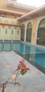 a building with a swimming pool with a flower in front of it at Janki Vilas in Orchha
