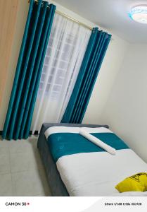 1 dormitorio con una ventana con cortinas azules en Kings Sapphire Appartments, en Nakuru
