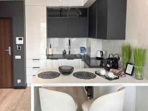 una cocina con armarios en blanco y negro y una mesa en Hanza Tower - Blue Heaven Apartment - pool, sauna, sunset view, en Szczecin
