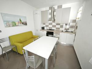 a kitchen with a white table and a yellow couch at Patrizia in Rosolina +2 photos