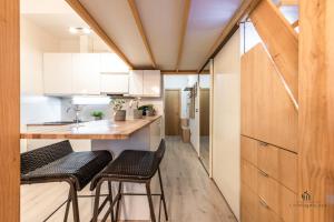 una cocina con armarios blancos y taburetes negros en Living4malaga Woodland Oasis, en Málaga