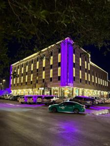een gebouw met paarse lichten voor een parkeerplaats bij الجوهرة بارك 1 in Riyad
