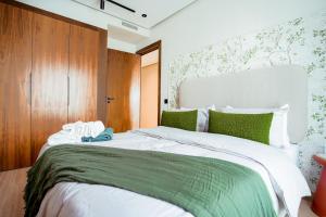 una camera da letto con un grande letto bianco con accenti verdi di Appartement Pro et Cosy parfait pour séjour d'affaires a Casablanca