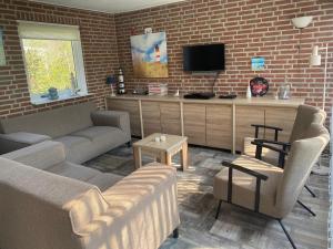 ein Wohnzimmer mit Sofa und Fernseher in der Unterkunft Meno Mosso in Sint Maartensvlotbrug