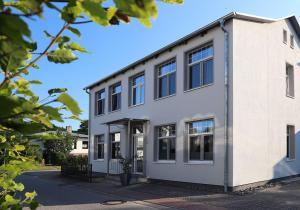 a white building with black windows on a street at Haus Seestern in Thiessow