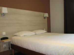 a bedroom with a bed with two pillows on it at Hôtel Montchapet Dijon Centre in Dijon