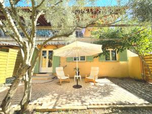 a patio with two chairs and an umbrella in front of a house at Les Gîtes du Petit Mas in Lagamas