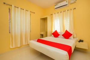 a bedroom with a large bed with red pillows at Hotel O Varcity Emerald Near Ragigudda Sri Prasanna Anjaneyaswamy Temple in Bengaluru +17 photos
