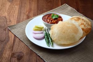 a plate of food with a sandwich and a bowl of chili at Hotel O Varcity Emerald Near Ragigudda Sri Prasanna Anjaneyaswamy Temple in Bengaluru
