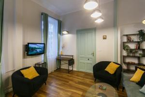 a living room with two chairs and a tv at Klimt's Puzzle Suite in Sofia