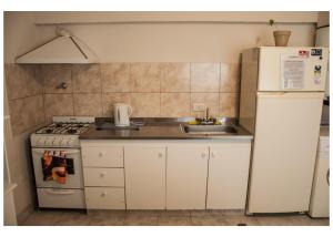 een keuken met een fornuis, een wastafel en een koelkast bij Hospedaje Los Macaes 2 in Comodoro Rivadavia +4 foto's