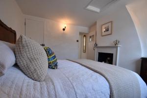 ein Schlafzimmer mit einem Bett mit zwei Kissen und einem Kamin in der Unterkunft Mim's Cottage in Rye