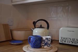 eine Küchentheke mit einem Wasserkocher und 2 Tassen in der Unterkunft Mim's Cottage in Rye