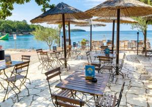 un gruppo di tavoli e sedie con ombrelloni in spiaggia di Camping Bijela Uvala - Eurocamp I Homair a Poreč (Parenzo) Altre 26 foto