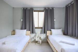 two twin beds in a room with a window at Cozy&Modern 6-BR Home, 14pax - Central, 5mins BTS in Bangkok
