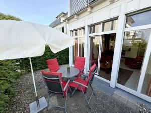 einen Tisch mit roten Stühlen und einem Regenschirm in der Unterkunft Haus Möwe I Whg 02 mit Terrasse in Ostseebad Sellin