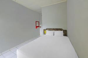a white bed with two pillows in a room at Hotel O Cipto Arum in Cilacap