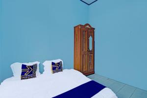 een slaapkamer met 2 bedden en een klok aan de muur bij SPOT ON 91918 Najla Guest House Syariah in Parit