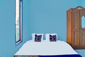 een blauwe slaapkamer met een bed en een houten kast bij SPOT ON 91918 Najla Guest House Syariah in Parit