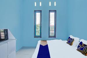 een blauwe kamer met een bed en ramen bij SPOT ON 91918 Najla Guest House Syariah in Parit +18 foto's