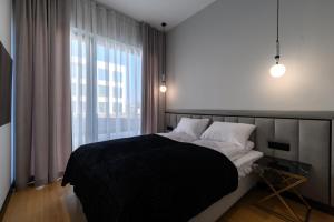 a bedroom with a black and white bed and a window at Nad zatoką Ukiel apartamenty przy jeziorze in Olsztyn +34 photos