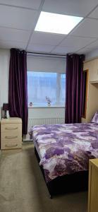 a bedroom with a bed and a window with purple curtains at Barton Beach First Floor Holiday Apartment Mablethorpe in Mablethorpe +19 photos