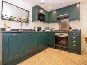 a kitchen with green cabinets and a sink at The Cabin at Ropewalk in St. Agnes