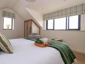 a bedroom with a white bed with a basket on it at The Cabin at Ropewalk in St. Agnes