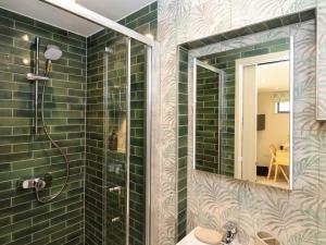a bathroom with green tiles and a shower with a mirror at The Cabin at Ropewalk in St. Agnes +15 photos