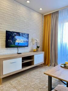 a living room with a flat screen tv on a brick wall at Квартира подобово Центр Руська in Ternopilʼ +10 photos