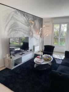 a living room with a tv and a couch and a table at BY NEPTUNE - Appartement Disneyland Paris in Chessy +8 photos