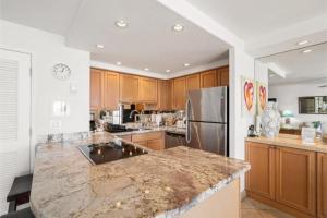 a kitchen with a marble counter top and a refrigerator at Kihei Beach, #603^ condo in Kihei +25 photos