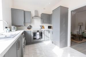 a kitchen with white cabinets and a white tile floor at The Ayton Hideaway in Great Ayton
