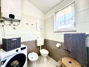 a bathroom with a washing machine and a toilet at Apartments Terra Solaris in Medulin