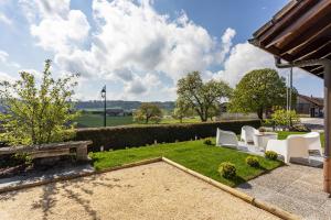 ein Garten mit weißen Stühlen und einem Rasen in der Unterkunft le19ème Vuissens in Vuissens
