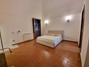 Schlafzimmer mit einem weißen Bett und Holzboden in der Unterkunft Guest house degli scalzi in Gaeta