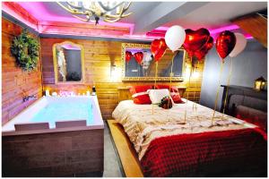 a bedroom with a bed and a tub with balloons at Le Chalet romantique, SPA XXL, Écran cinéma, Lit king size, cascade d'eau in Bourgoin +14 photos