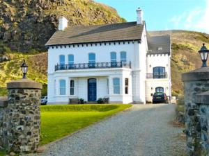 a large white house on a hill with a driveway at Downhill Beachhouse Group Accommodation in Castlerock