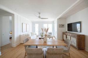 una sala de estar blanca con mesa de madera y sillas en Allure by Mira-Mar, en Wrightsville Beach