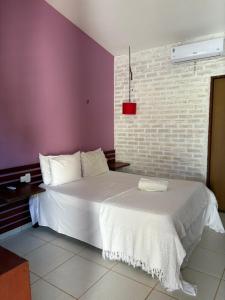 een slaapkamer met een wit bed en een bakstenen muur bij Amar são Miguel Pousada in São Miguel do Gostoso