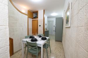 een eetkamer met een witte tafel en groene stoelen bij Casa Indaterr in Mola di Bari