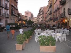 a group of people walking down a street with tables and chairs at Case Vacanze Ancora in Porto Empedocle