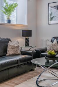 a living room with a black leather couch and tables at Union Row Retreat - SJA Stays - Luxury 1 Bed Apartment in Aberdeen