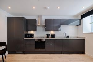 a kitchen with black cabinets and a sink at Union Row Retreat - SJA Stays - Luxury 1 Bed Apartment in Aberdeen
