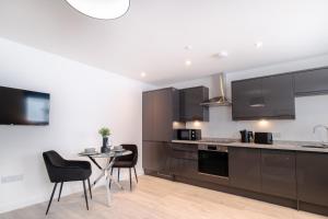 a kitchen with black cabinets and a table and chairs at Union Row Retreat - SJA Stays - Luxury 1 Bed Apartment in Aberdeen +24 photos