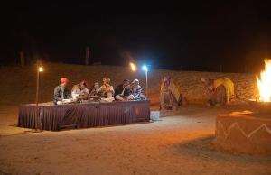 a group of people sitting on a table at night at Osian Desert Camp Safari in Osiān