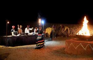 a group of people sitting around a table with fire at Osian Desert Camp Safari in Osiān